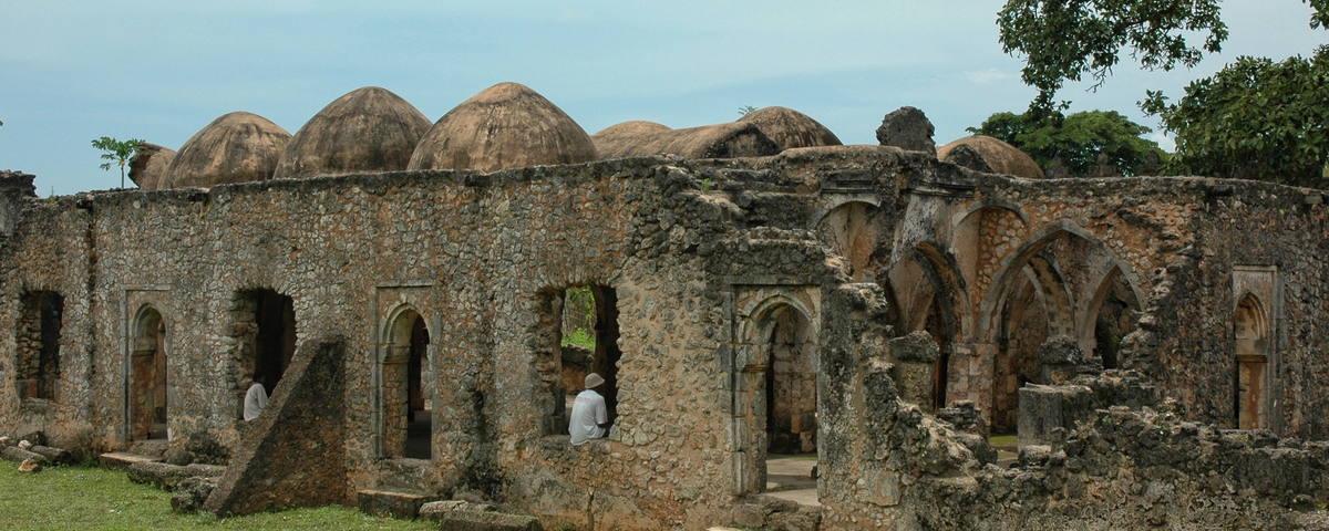 Braune alte Steinruine mit Kuppeln, Fenstern und einer Person