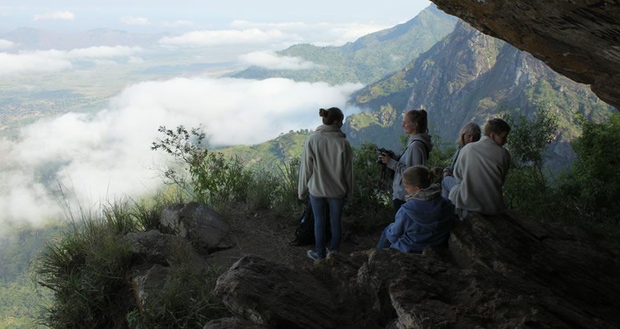 Gruppe Wanderer sitzt auf Felsen, Berg und Wolken im Hintergrund