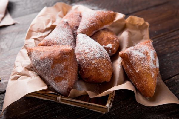 Mandazi mit Puderzucker auf braunem Papier
